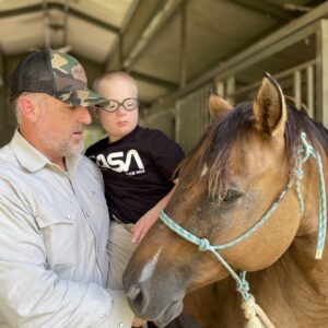 Man holding young child next to a horse